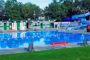 Photo of outdoor pool. View includes six-lane pool, waterslide and pool house.